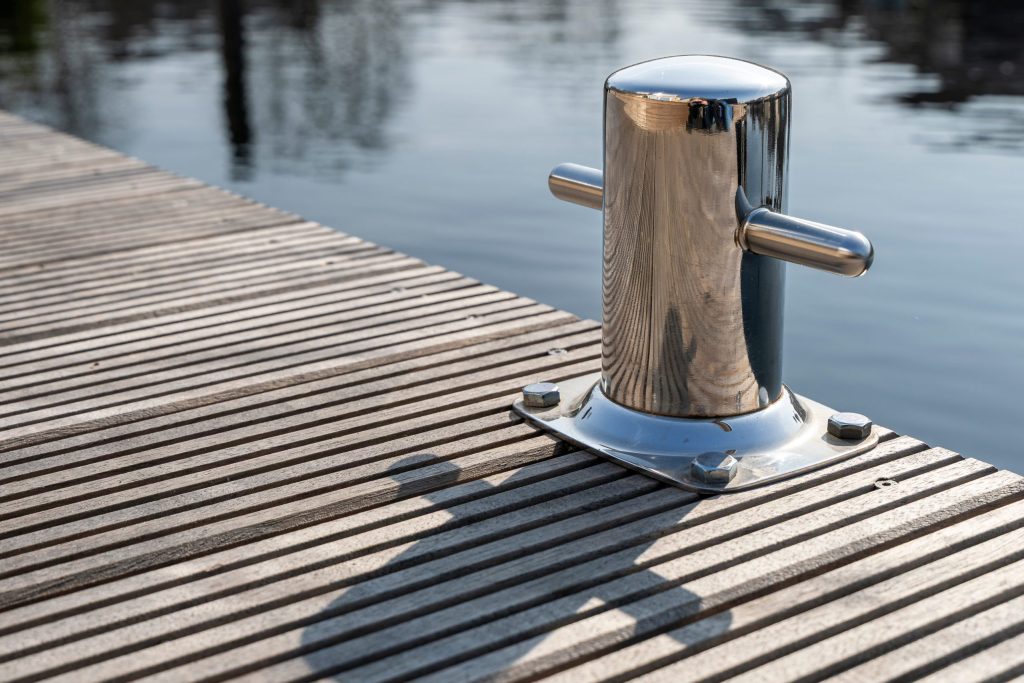 Houten meerpaal met RVS beslag geïnstalleerd op een houten steiger aan het water