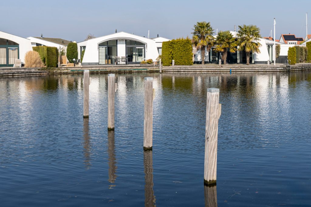 Moderne watervilla's met steigerwerk en houten meerpalen langs privé kanaalsysteem in luxe woonwijk