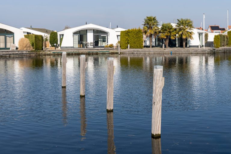 Moderne watervilla's met steigerwerk en houten meerpalen langs privé kanaalsysteem in luxe woonwijk