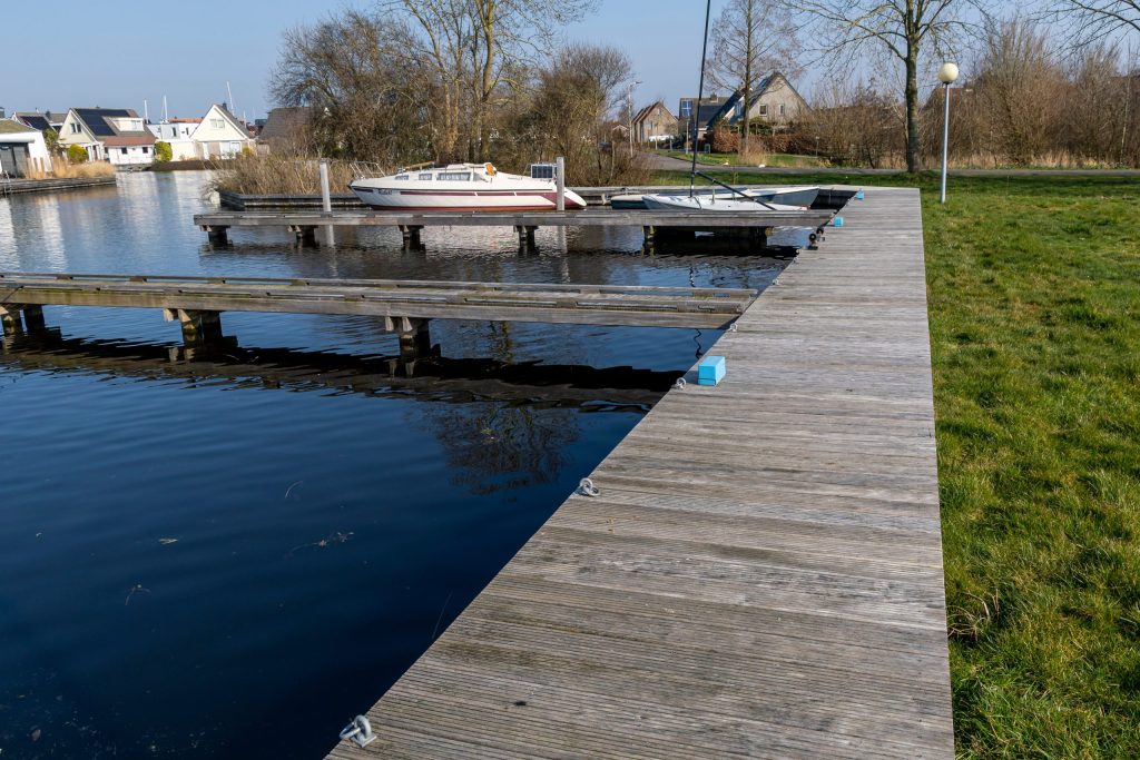 Houten steiger met aanlegplaatsen voor boten aan het water met meerpalen en ligplaatsen
