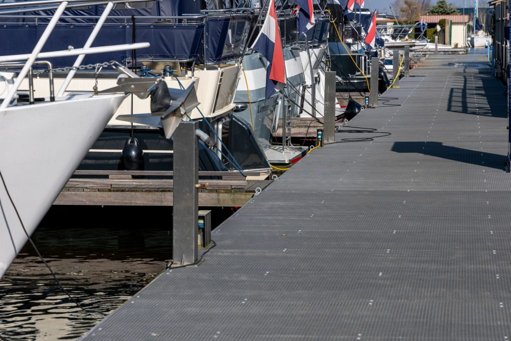 Drijvende steiger met afgemeerde jachten en boten in jachthaven met moderne kunststof vlonders