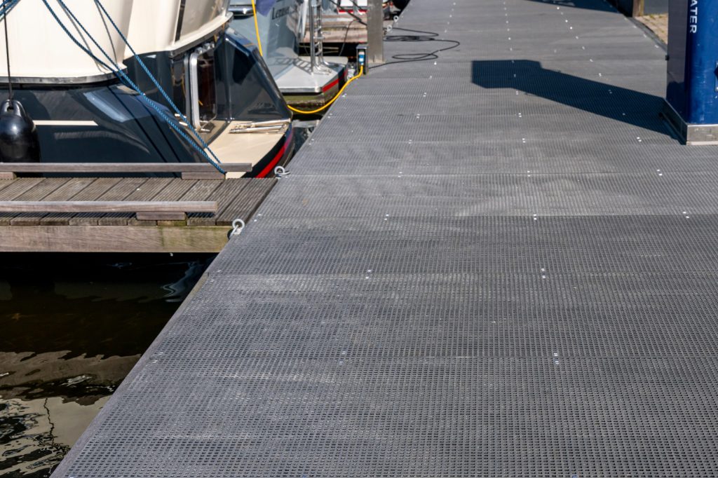 Kunststof pontons steiger met antislip loopvlak langs aangemeerde boten in jachthaven