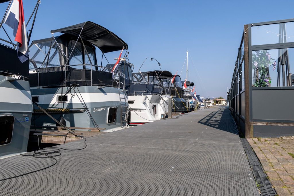Drijvende steigers met aangemeerde plezierboten in moderne jachthaven met toegangspoort