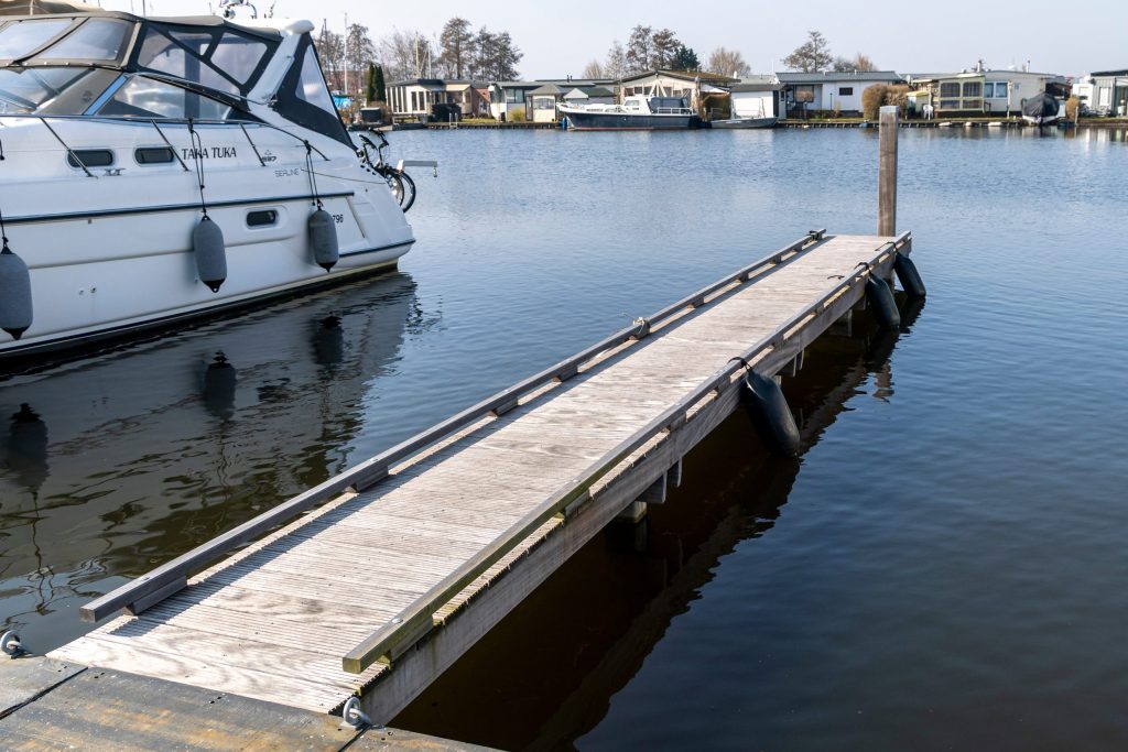 Houten pontonsteiger met bootligplaats in jachthaven met afgemeerde boot