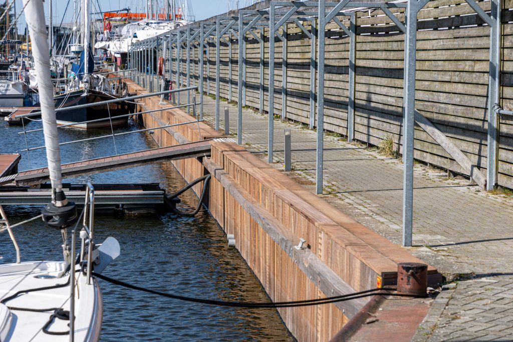 Houten drijvende steigers met metalen leuningen in jachthaven voor aanlegplaatsen van boten en jachten