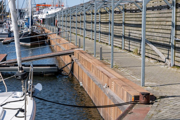 Houten drijvende steigers met metalen leuningen in jachthaven voor aanlegplaatsen van boten en jachten