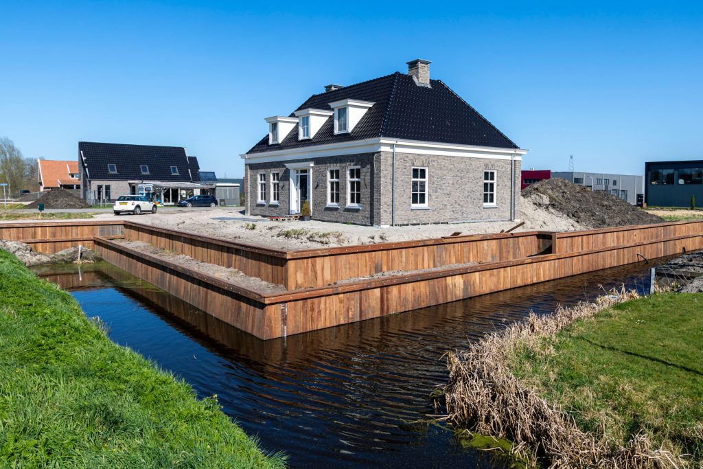 Houten beschoeiing rondom woning met water, aangelegde damwand voor oeverbescherming nieuwbouwwijk