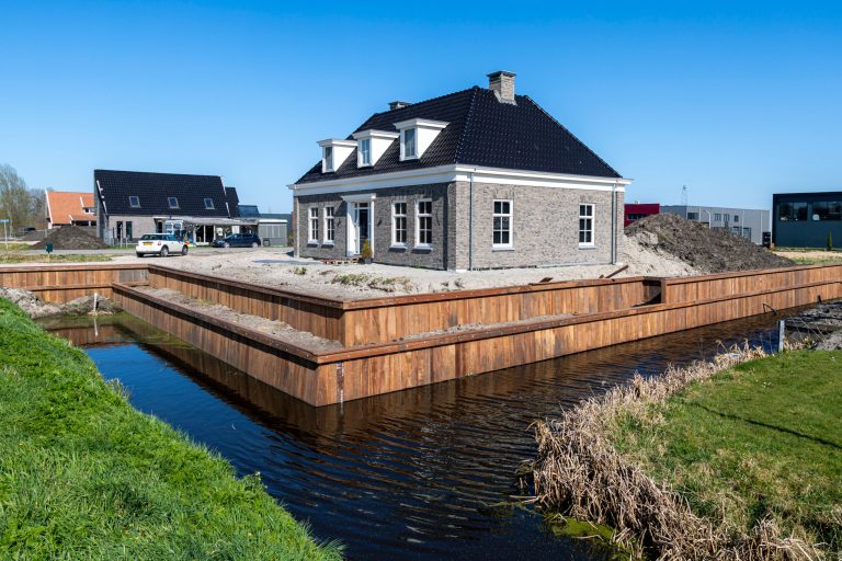 Houten beschoeiing rondom woning met water, aangelegde damwand voor oeverbescherming nieuwbouwwijk